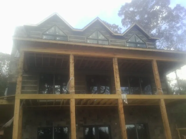 Dormers and porch framing on a large log home under construction — Roof Coating work by our crew in Ottertail