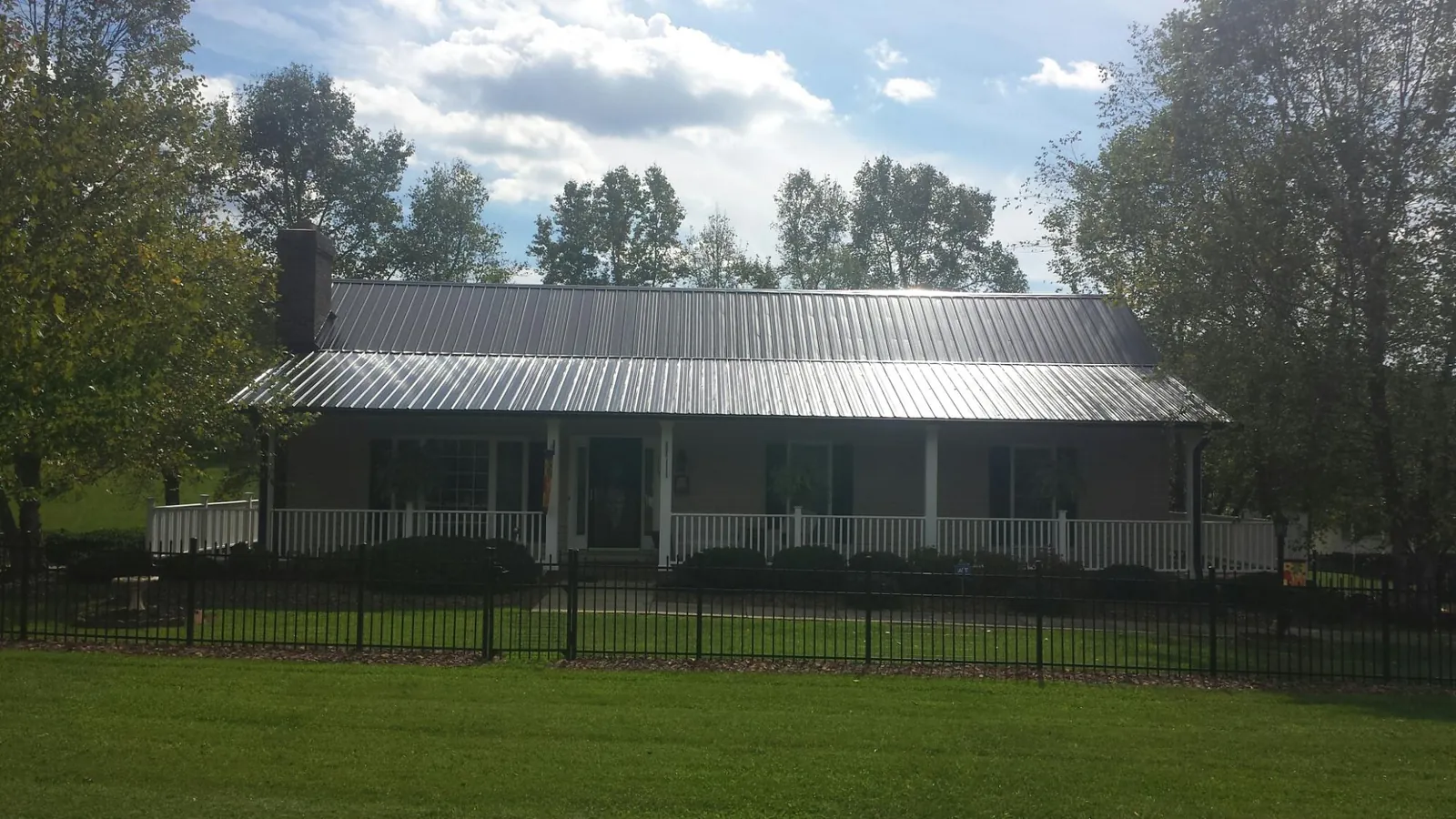 Gray metal roof on a brick ranch with a full width front porch — Gutter Guard Installation work by our crew in Ottertail