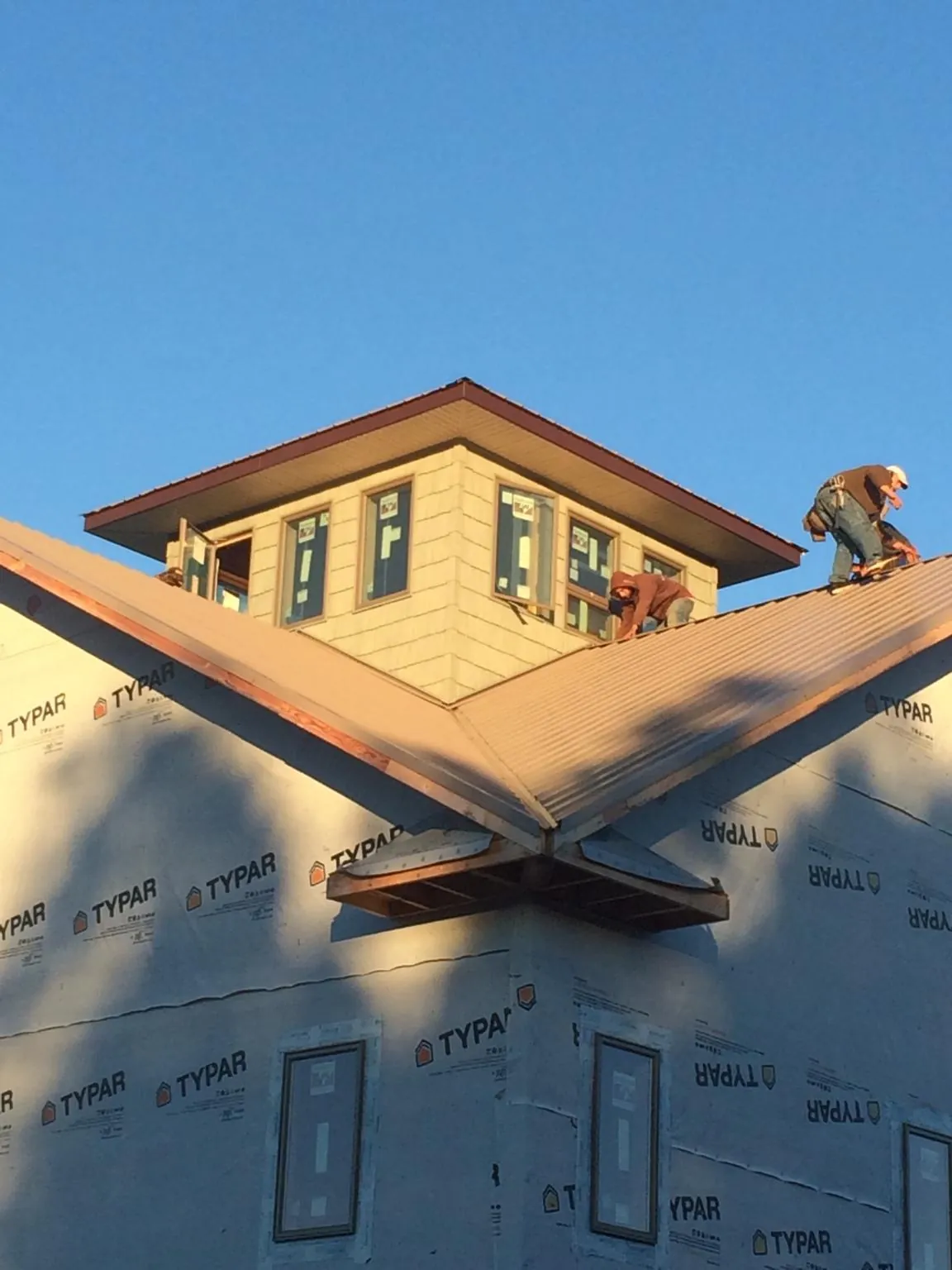 Roofers working around a rooftop cupola on a new metal roof at sunset — Roof Waterproofing in Ottertail by Roofing Brothers